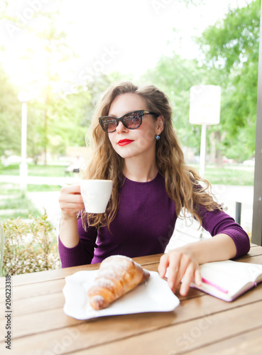 Young woman drinking coffee in city cafe photo