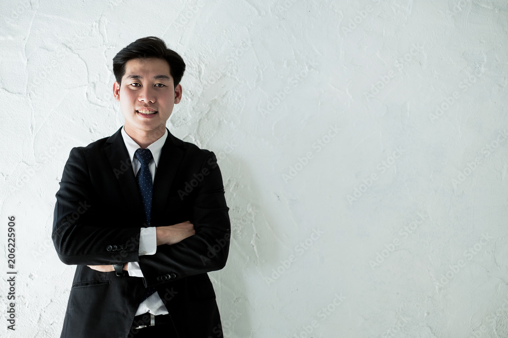 Young businessman with crossed arms standing near the office window, business concept Young businessman with crossed arms standing near the office window, business concept