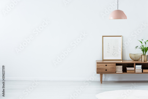 Pink lamp above wooden sideboard