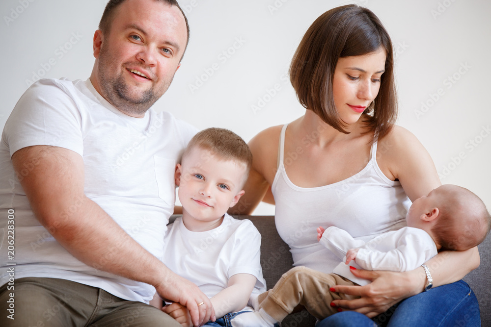 Image of happy married couple with two young sons sitting on sofa Image of happy married couple with two young sons sitting on sofa