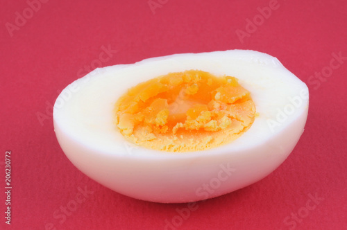 un œuf dur coupé en deux sur fond rouge