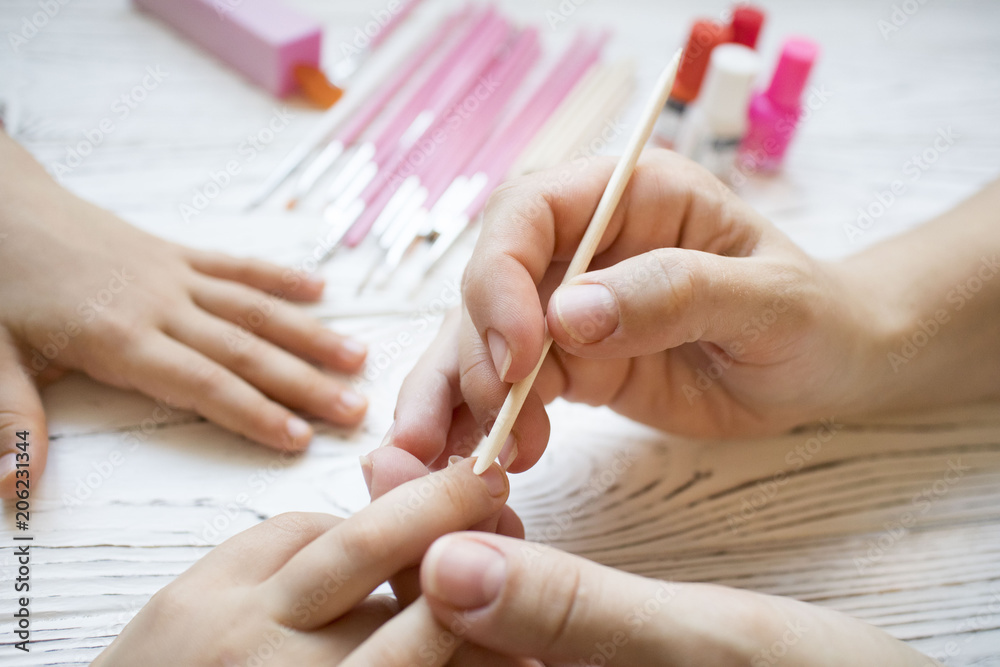 mom does baby manicure on white wooden table, beautiful nails mom does baby manicure on white wooden table, beautiful nails