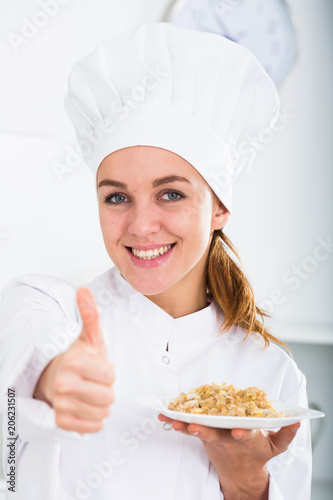 portrait of young coosie woman showing mush at kitchen photo