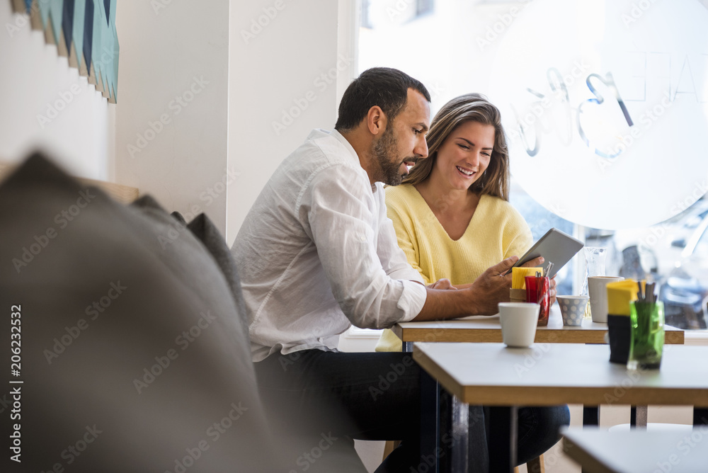 Young woman and man sharing tablet in a cafe Young woman and man sharing tablet in a cafe