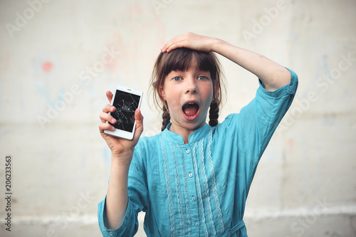 Broken glass screen smartphone in hand of upset girl, white background.