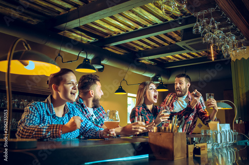 Sport  people  leisure  friendship and entertainment concept - happy football fans or male friends drinking beer and celebrating victory at bar or pub