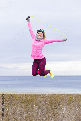 Woman training outdoor with jump rope on cold day