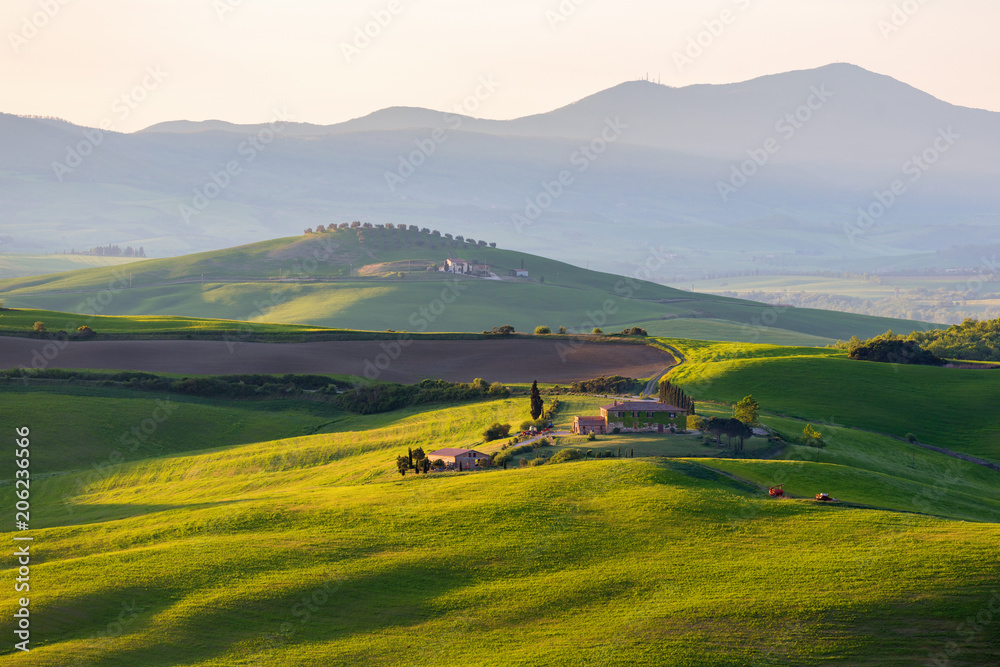 Sunlit field with a farm in Tuscany, Italy
