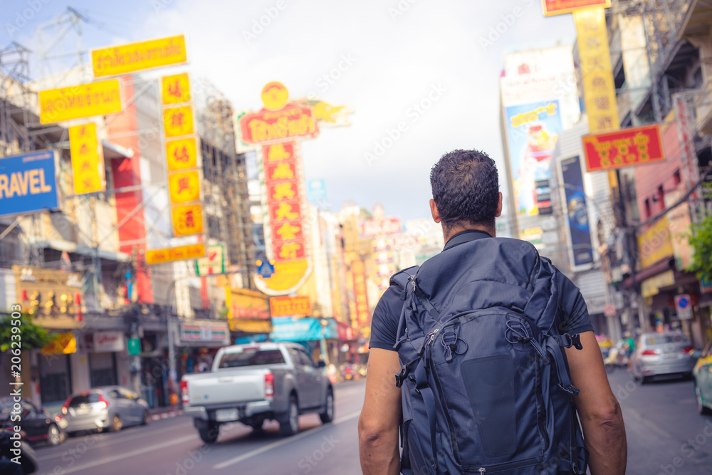 Fototapeta premium men backpacker looking at the famous place of Yaowarat road in Chinatown Bangkok during day, Thailand , Southeast asia .