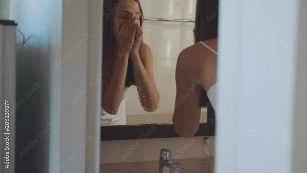 Young woman is washing herself face at home in the morning Young woman is washing herself face at home in the morning
