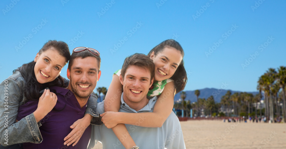 summer holidays, tourism and travel concept - group of happy friends or couples over venice beach background in california