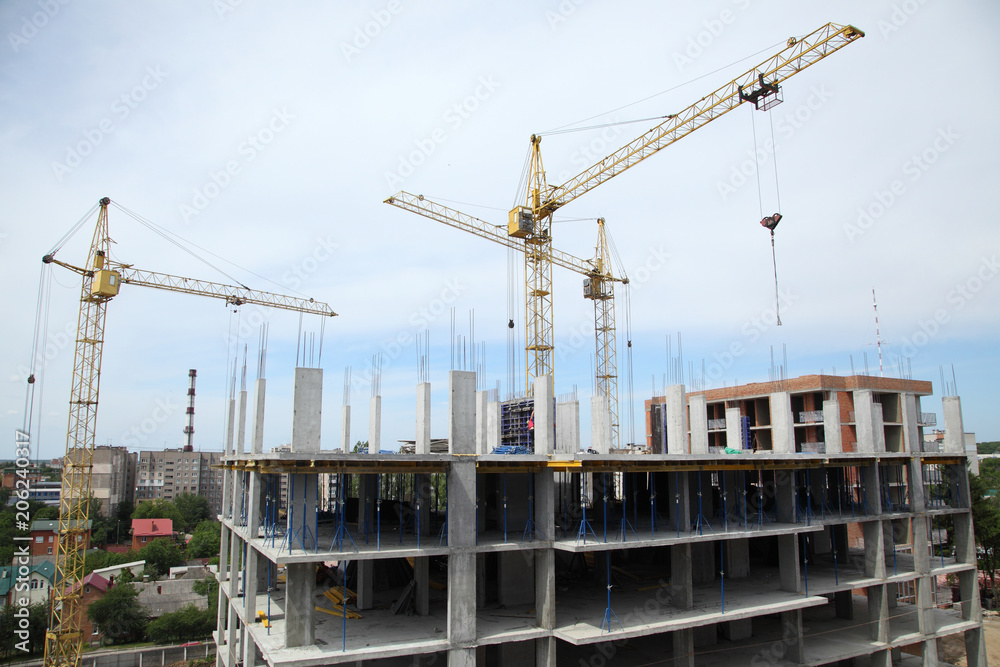 A modern new building. Working crane on the construction of the house. Construction site with cranes on sky background. A modern new building. Working crane on the construction of the house. Construction site with cranes on sky background.