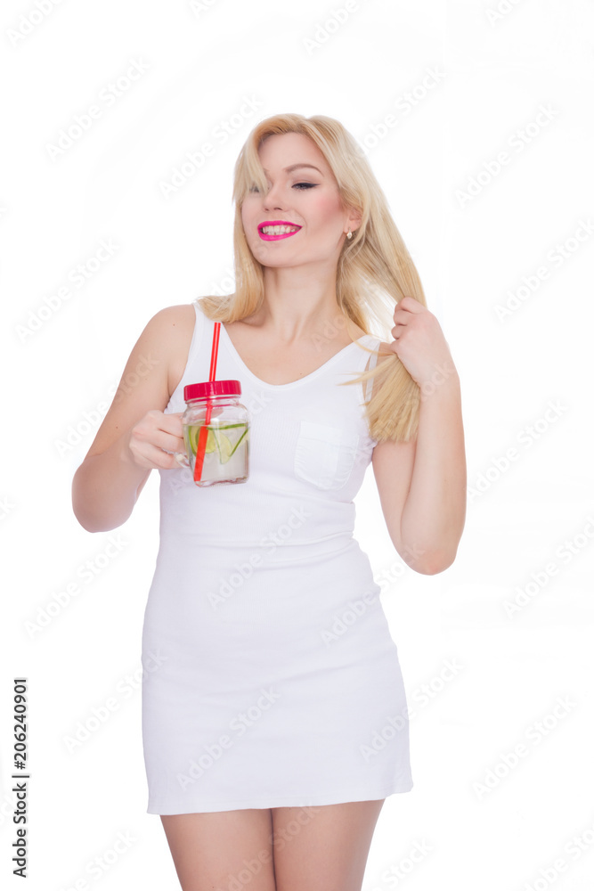 A friendly blond woman holds a glass of water and lime in her hands. A girl is drinking lemonade. Concept - healthy food, thirst quenching in summer A friendly blond woman holds a glass of water and lime in her hands. A girl is drinking lemonade. Concept - healthy food, thirst quenching in summer