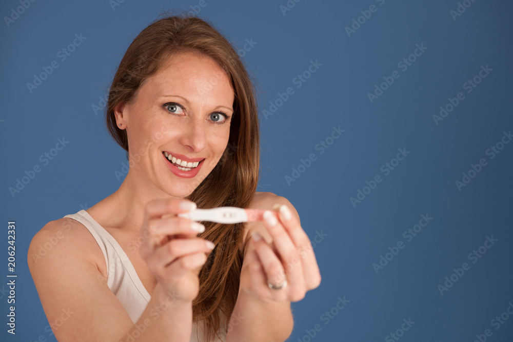 Happy woman with pregnancy test isolated over blue background Happy woman with pregnancy test isolated over blue background