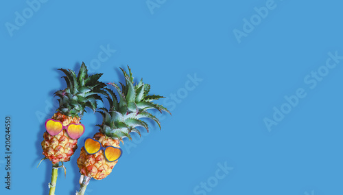 Minimal summer concept of couple pineapples and sunglasses on blue background with copy space