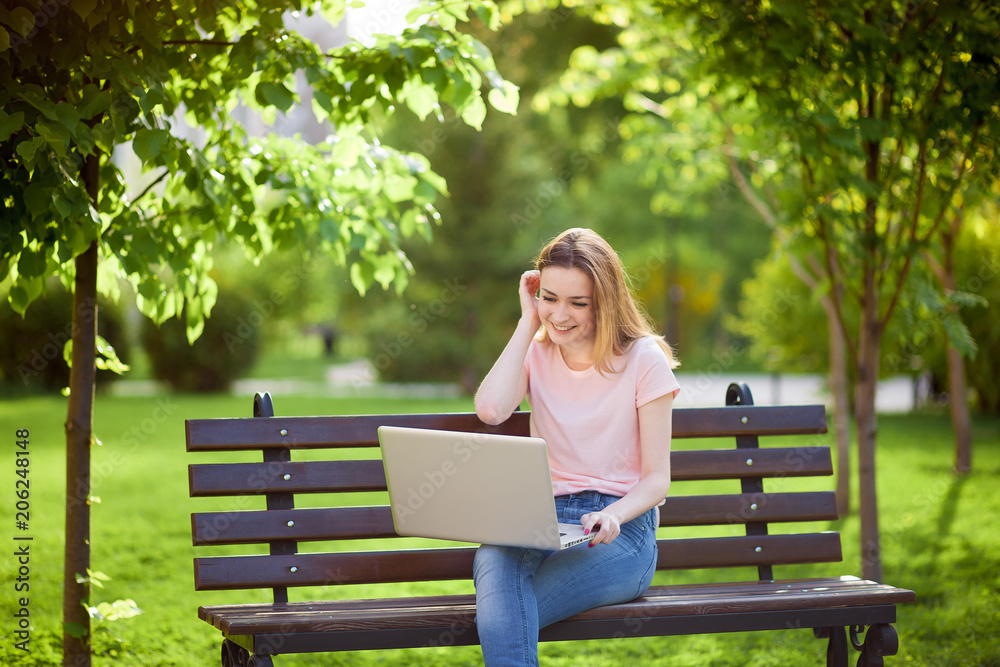 Girl with a laptop sitting on a bench in the Park Girl with a laptop sitting on a bench in the Park