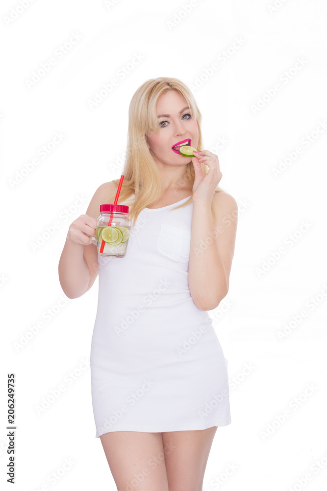 A woman on a white background holds a glass with lemonade in one hand, and in the second hand holds a piece of lime A woman on a white background holds a glass with lemonade in one hand, and in the second hand holds a piece of lime