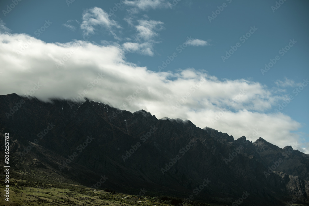 Landscape of shady mountains with huge clouds over them. day shot with blue sky.