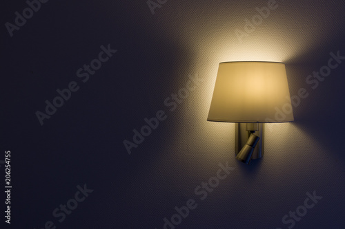 Wall lamp, night light in a dark background, yellow shade.