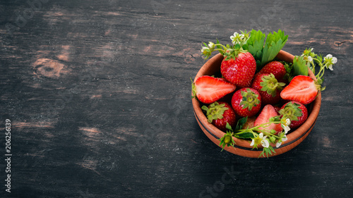 Strawberries in a plate. On a wooden background. Top view. Copy space.