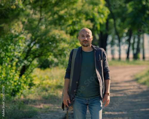 Fototapeta Naklejka Na Ścianę i Meble -  bald bearded man walks through the park.