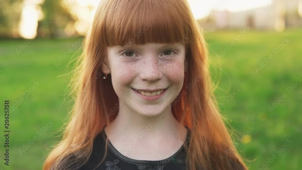 Little beautiful redhead girl with freckles smiling and looking at camera Little beautiful redhead girl with freckles smiling and looking at camera
