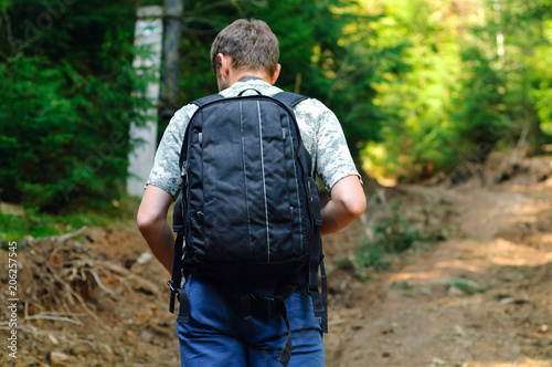 man with black backpack traveling in the mountains, travel concept in the wild, copy space, closeup, © Nataliia