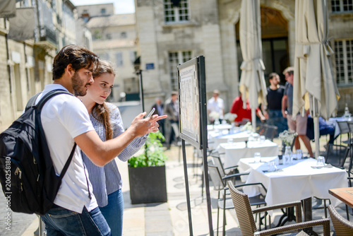 Canvas Print cheerful young couple looking at restaurant menu on a cultural weekend city trip