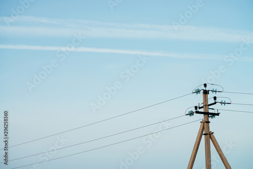 Power lines on background of blue sky close-up. Electric hub on pole. Electricity equipment with copy space. Wires of high voltage in sky. Electricity industry.