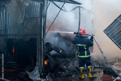 Firefighters on fire. Fireman extinguishes the fire with water. External market is on fire. photo