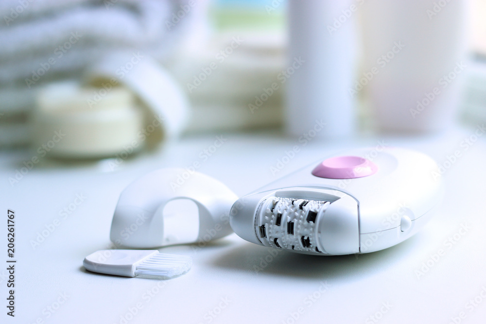 A modern epilator on the background of the bathroom interior. A modern epilator on the background of the bathroom interior.