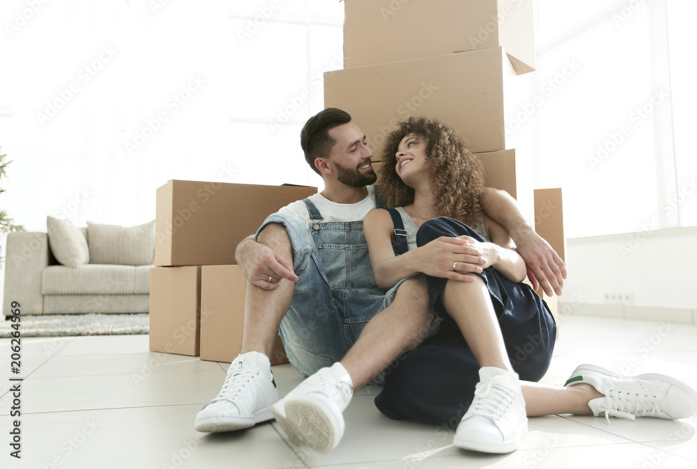 married couple sitting near cardboard boxes in a new apartment married couple sitting near cardboard boxes in a new apartment