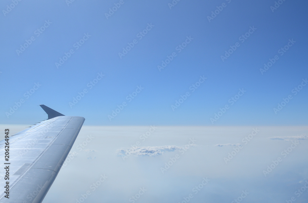 Fototapeta premium Part of an airplane wing, cloudscape and blue sky