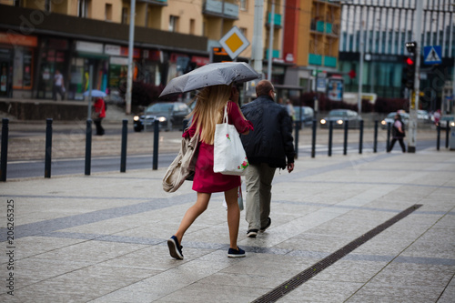 A young girl walks in the rain down the street