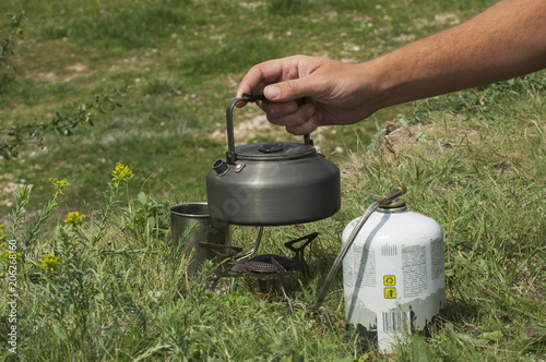 A tourist puts the kettle with water on the gas stove