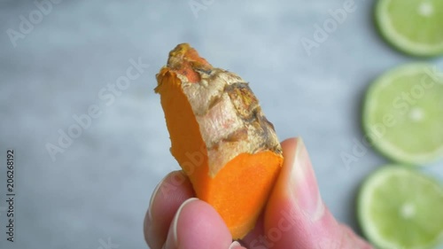 Macro shot of woman holding fresh turmeric root in 4k. The woman inspects the bright orange spice before blending it into golden milk. Closeup represents health benefits and holistic medicine. photo