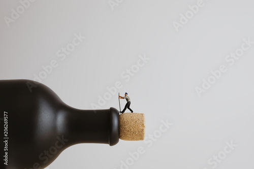 Closeup of a miniature worker opening a bottle photo