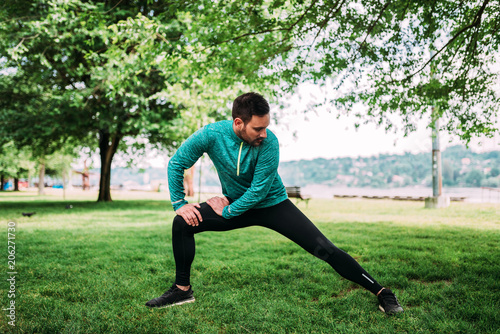 Young man in sportswear doing stretch exercises outdoors.