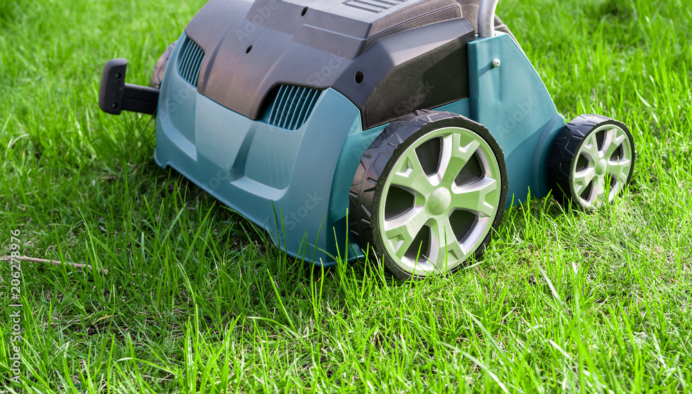 Fototapeta premium Scarifier on green grass. Work in the garden. scarifier