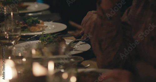 Man cutting steak at restaurant at night with candles
