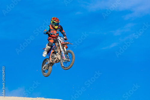 racer on a motorcycle in flight, jumps and takes off on a springboard against the sky.
