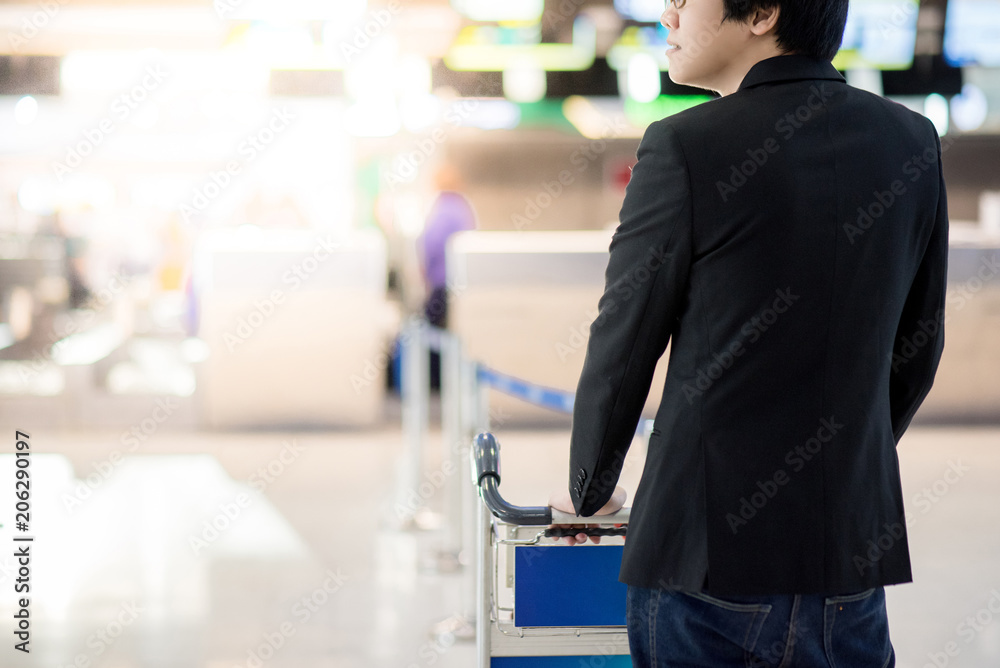 Young asian businessman with his luggage on airport trolley waiting for check in at airline counter in the international airport terminal, business travel concept Young asian businessman with his luggage on airport trolley waiting for check in at airline counter in the international airport terminal, business travel concept