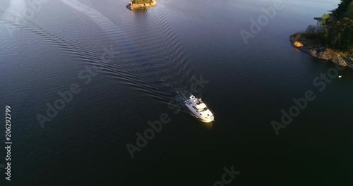 Boat in the archipelago C4k aerial view away from a motorboat on the gulf of finland, in tammisaari saaristo, between finnish islands, on a sunny spring evening dawn, in Uusimaa, Suomi photo