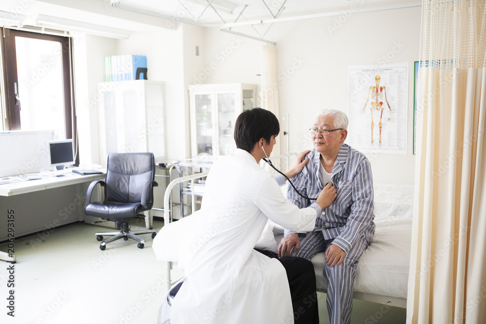 医療用ベッドで医師の診断を受ける高齢者の男性。 医療用ベッドで医師の診断を受ける高齢者の男性。