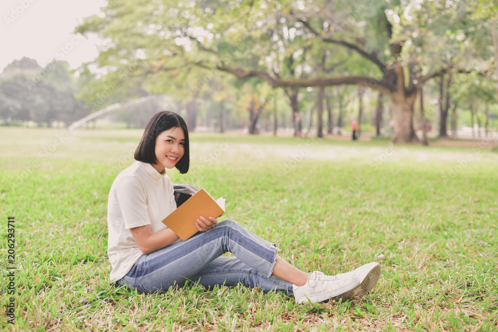 Education Concepts. Asian women reading books in the park. Beautiful women are relaxing in the park. Beautiful women are happy to read.