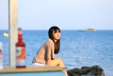 portrait of teenage asian girl sitting on the stone near the sea