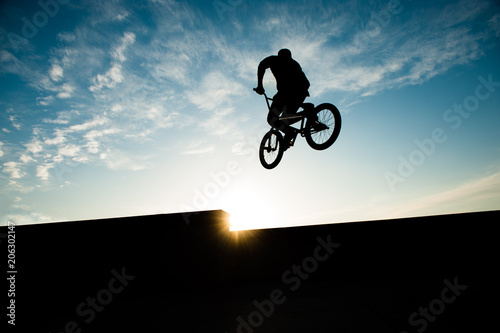 silhouette of jumping biker on summer sunset with copy space