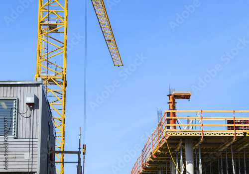 Construction crane tower on blue sky background. Crane and building working progress. Worker. Empty Space for text. Construction concept. Site. New buildings with a crane. Tower crane