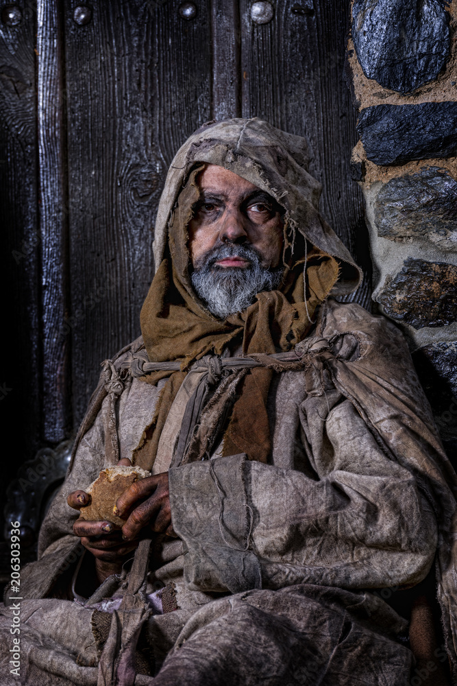 Man, dressed in rags, begging through the streets of a village Man, dressed in rags, begging through the streets of a village