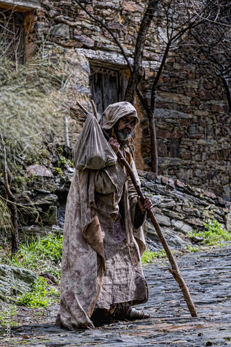 Man, dressed in rags, begging through the streets of a village
